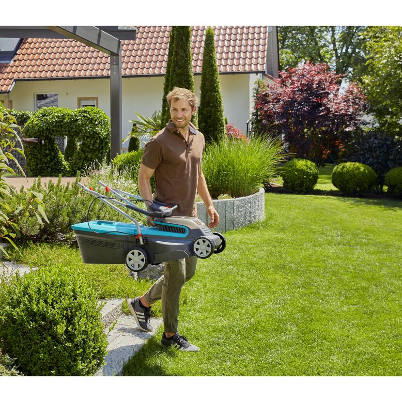 Person trägt Akku-Rasenmäher PowerMax Li-18/32
