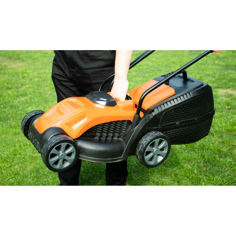 Person trägt orange-schwarzen Akku-Rasenmäher.
