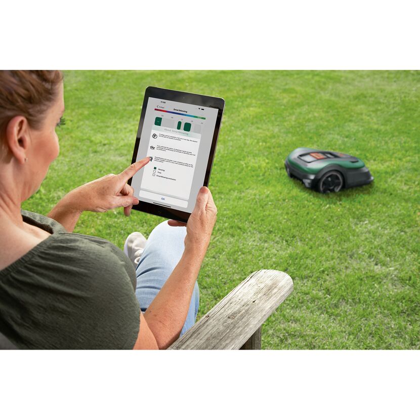 Person steuert Mähroboter per App