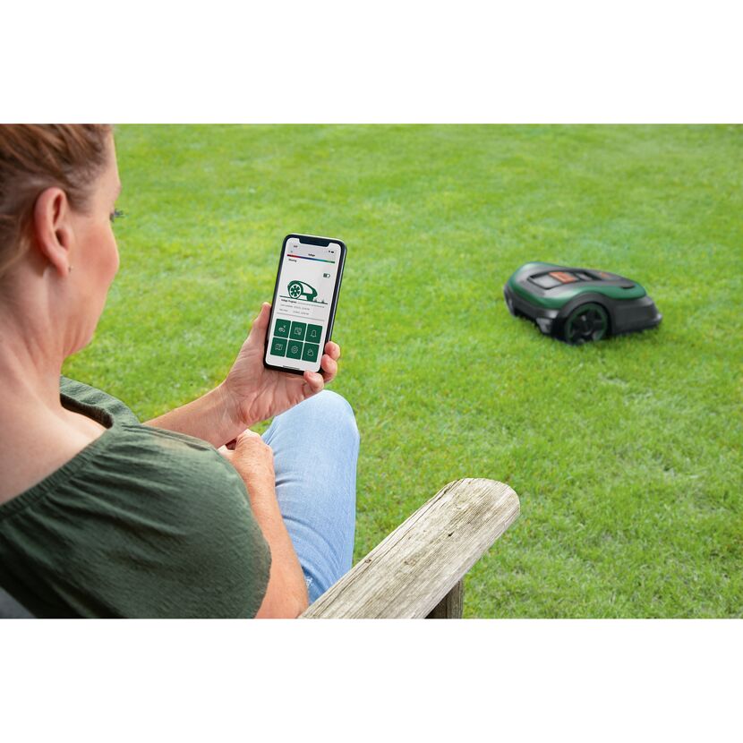 Person steuert Mähroboter per App