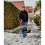 Person streut mit Streuwagen Schnee und Eis von der Auffahrt.