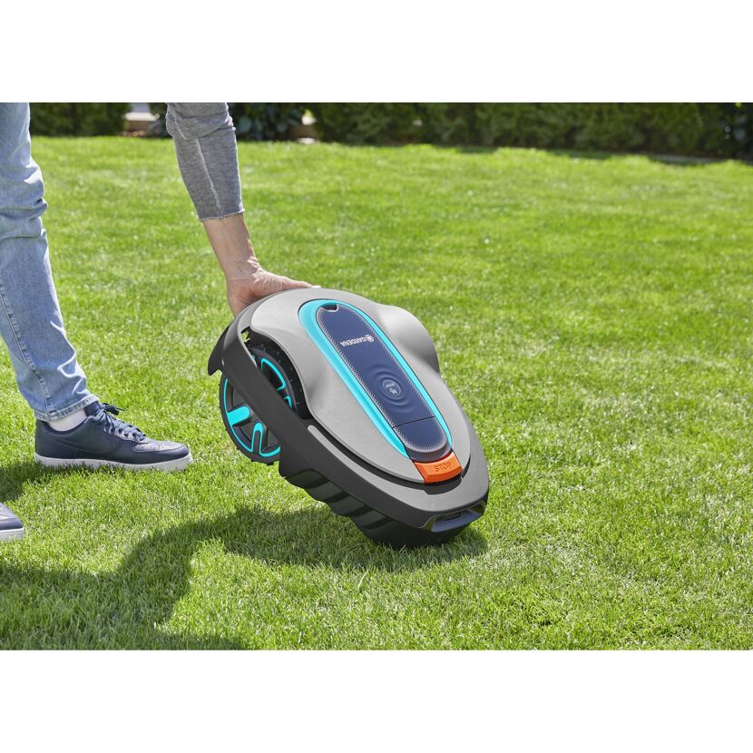 Person hebt Mähroboter SILENO city vom Rasen hoch.