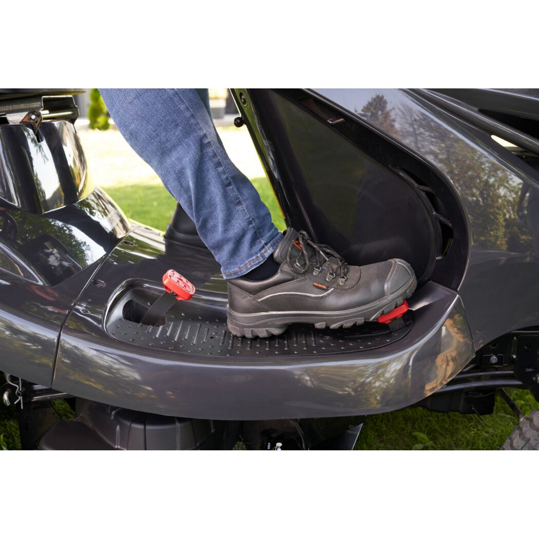Fuß eines Menschen auf dem Pedal eines Rasentraktors