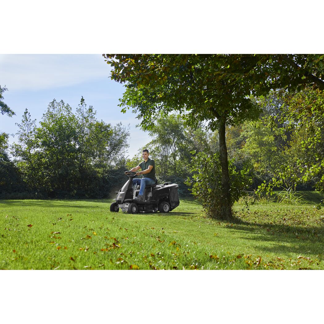 Person mäht Rasen mit Rasentraktor
