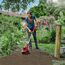 Person bearbeitet mit Bodenhacke den Gartenboden.