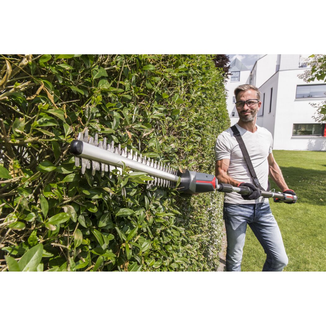 Person schneidet eine Hecke mit einer Heckenschere.