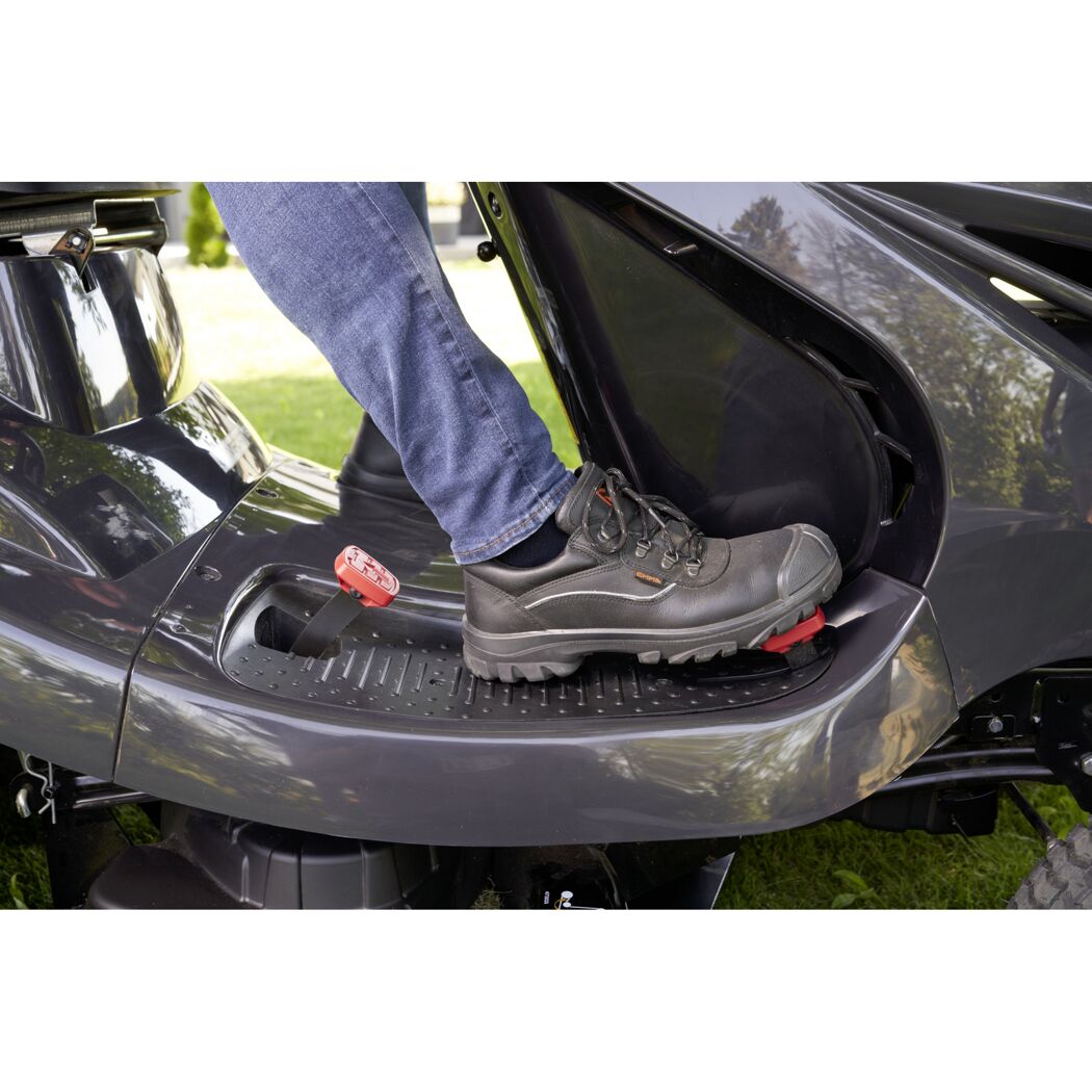 Fuß eines Menschen auf dem Pedal eines Rasentraktors