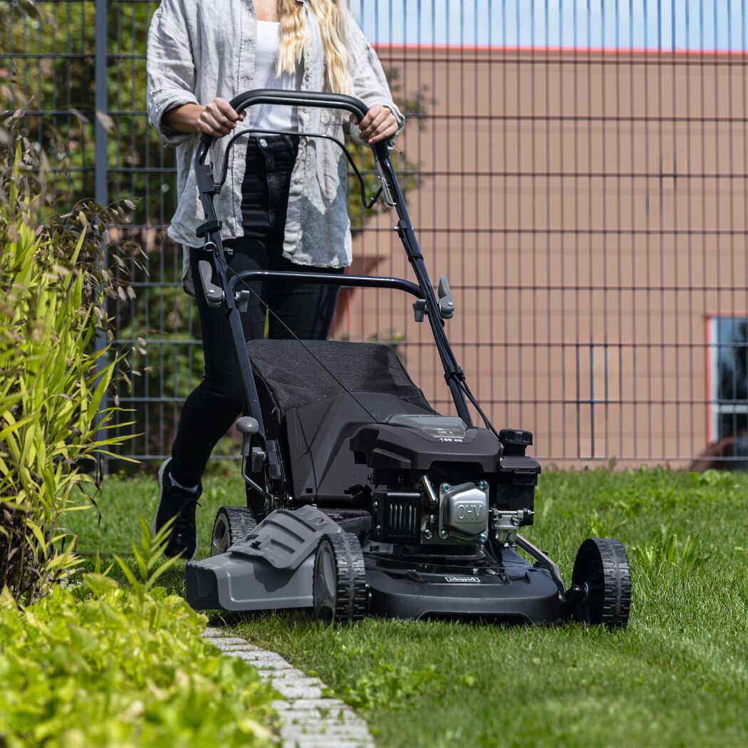 Person mäht Rasen mit Benzin Rasenmäher
