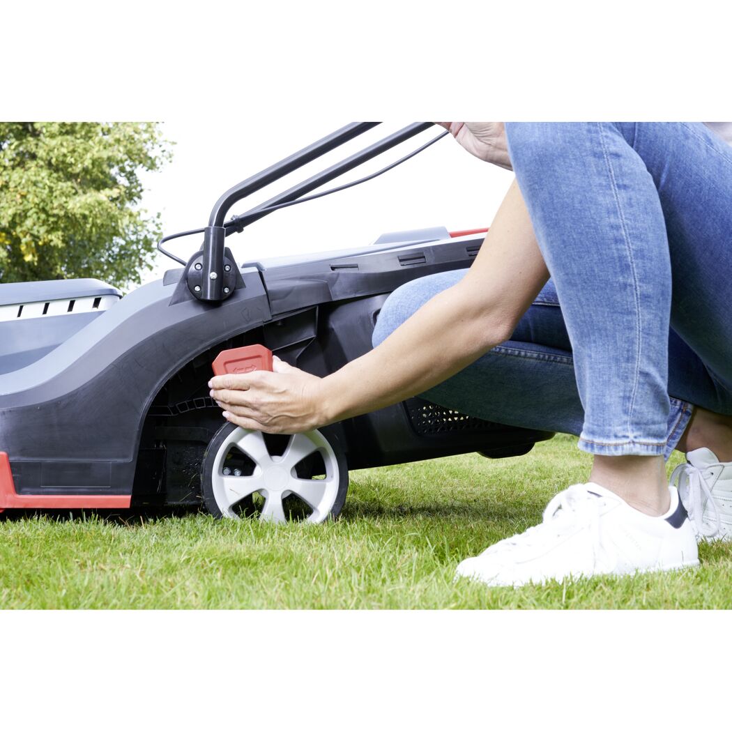 Person justiert Elektro-Rasenmäher