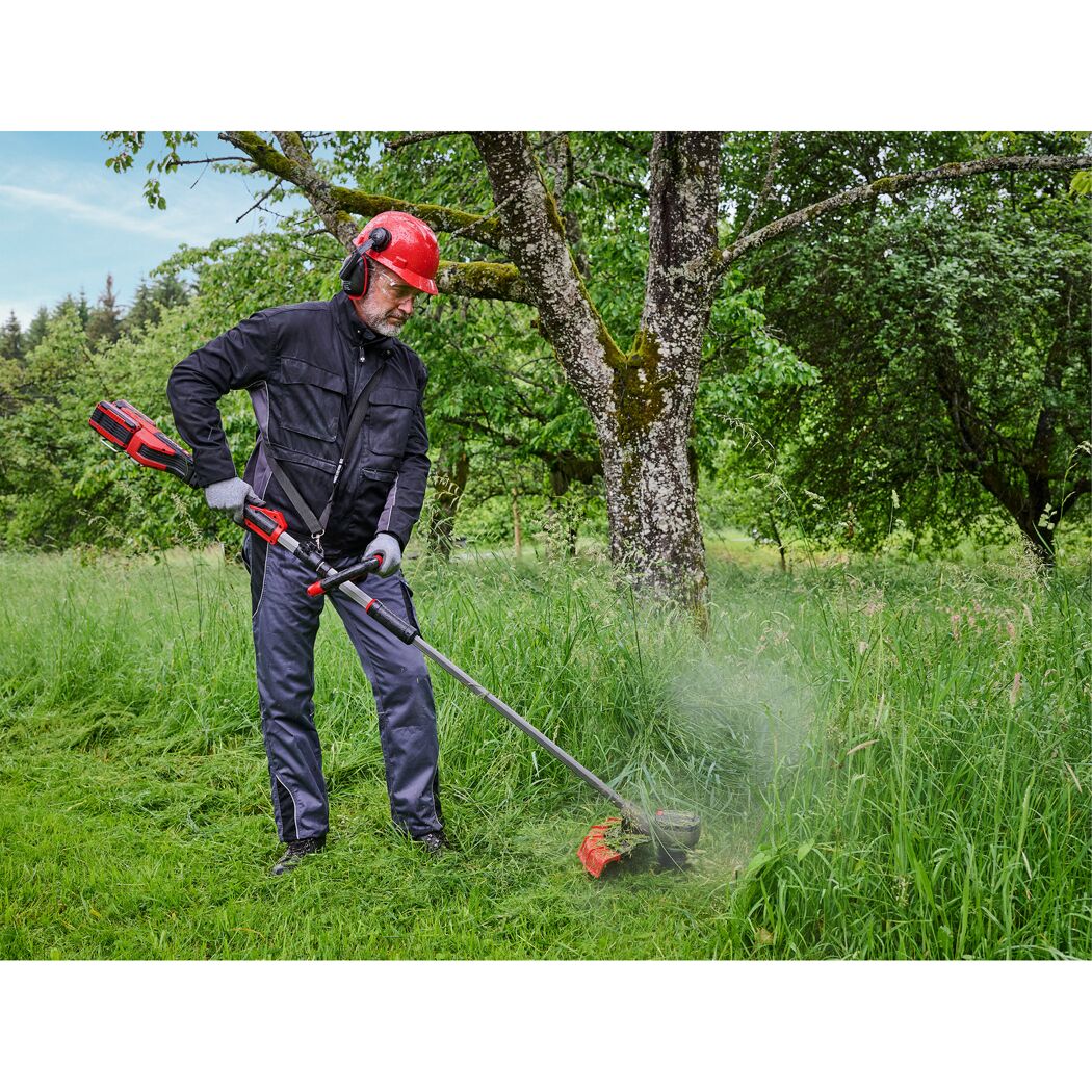 Person mäht hohes Gras mit Freischneider