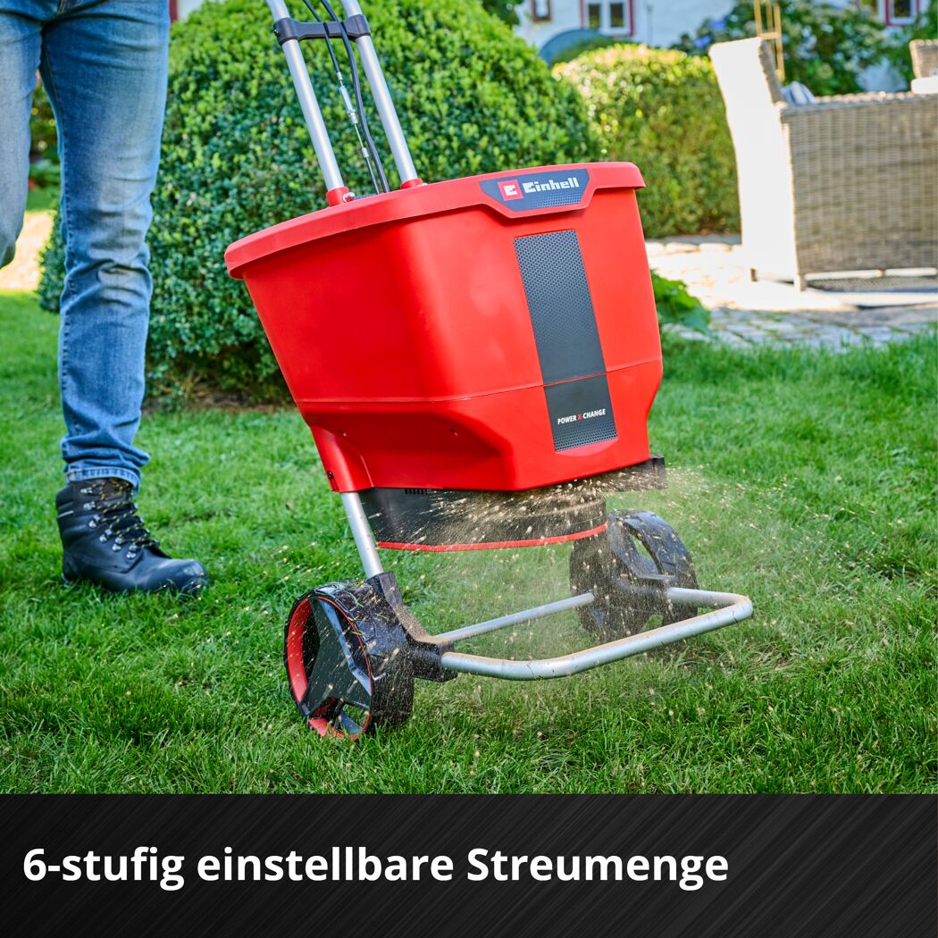 Person streut Dünger mit Streuwagen