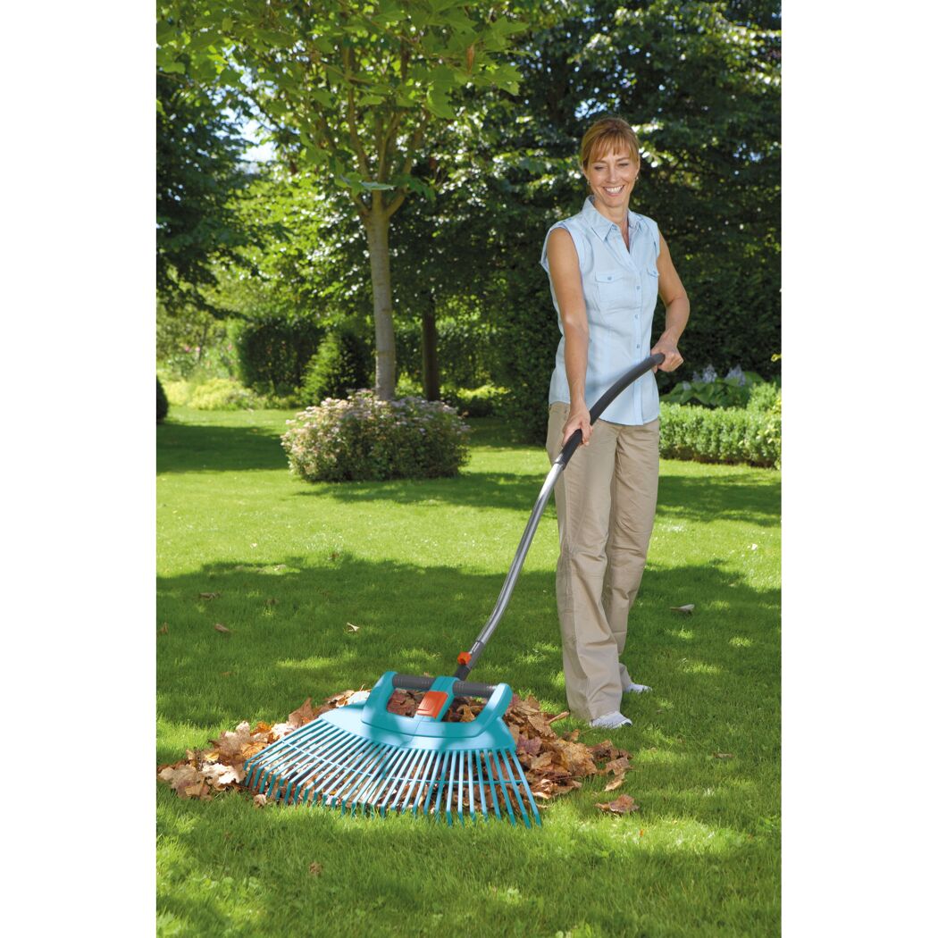 Person verwendet Laubbesen im Garten.