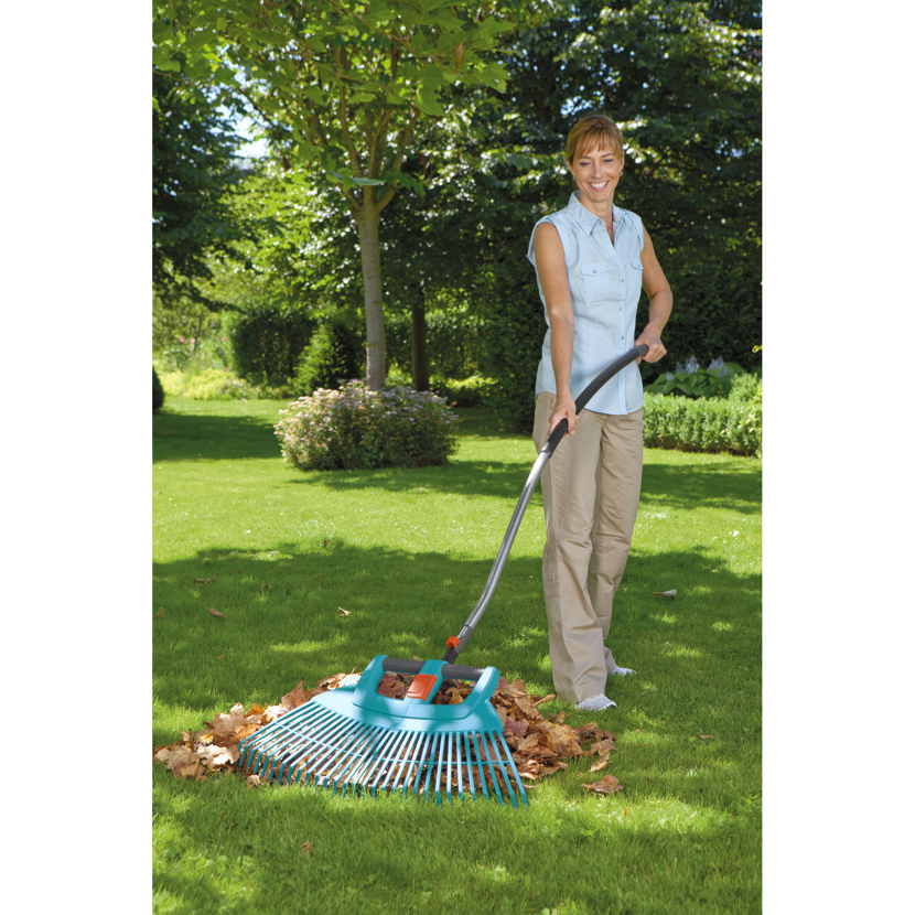 Person verwendet Laubbesen im Garten.