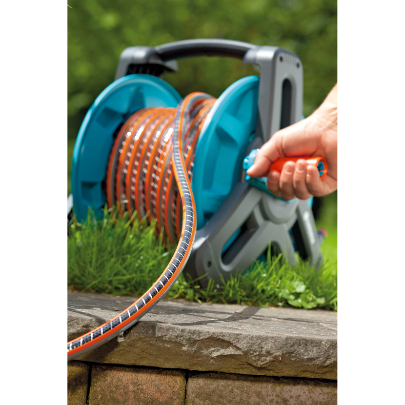 Person wickelt Gartenschlauch auf eine Schlauchtrommel.