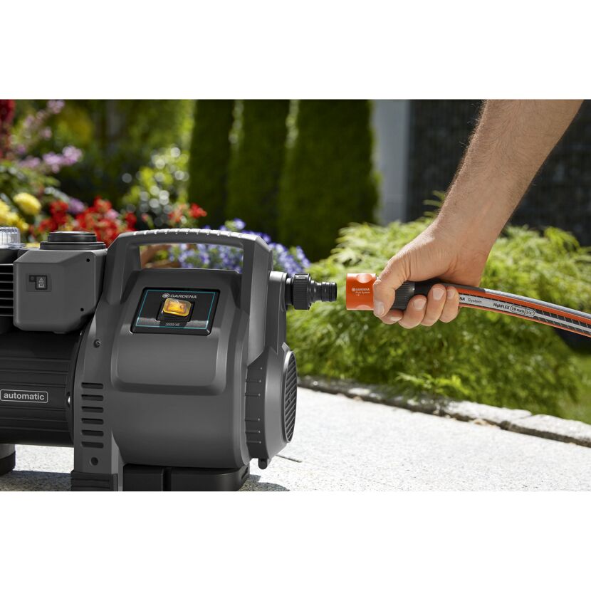 Person befestigt einen Gartenschlauch an einer Gartenpumpe.