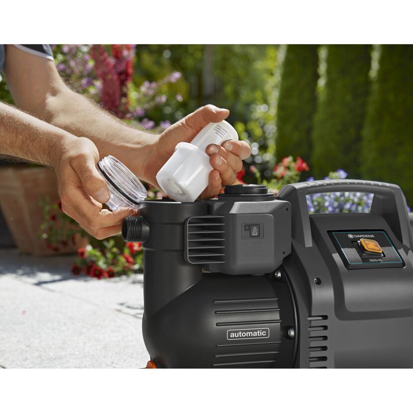 Person reinigt den Filter eines Hauswasserautomaten von GARDENA