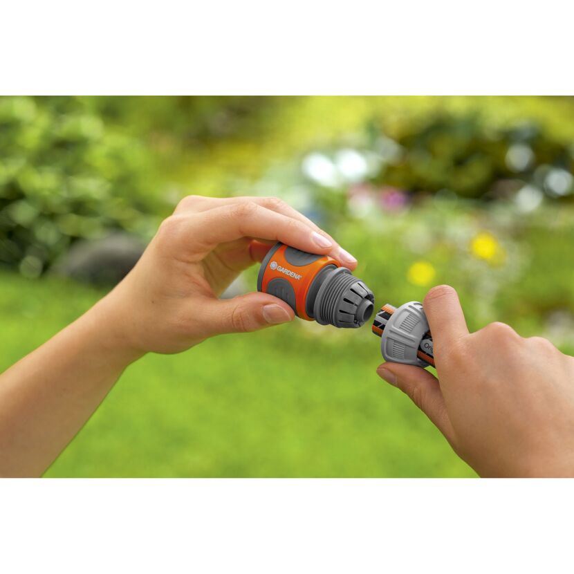 Person verbindet zwei Gartenschlauch-Teile.