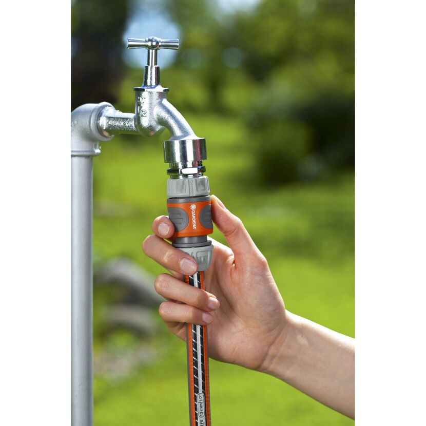 Person befestigt einen Schlauchanschluss an einen Wasserhahn.