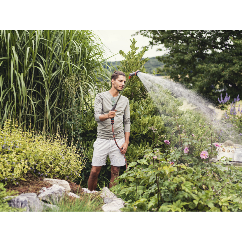 Person gießt mit Comfort Giessstab Pflanzen im Garten.