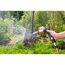 Person reinigt einen Spaten mit einem Gartenschlauch.