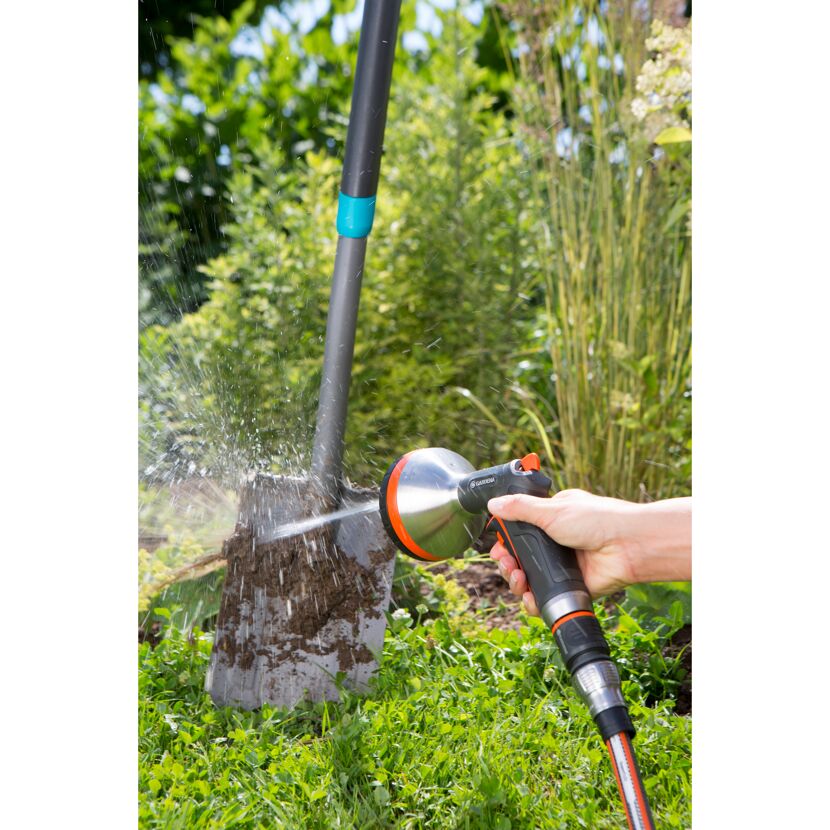 Person reinigt einen Spaten mit einer GARDENA Gartenbrause.