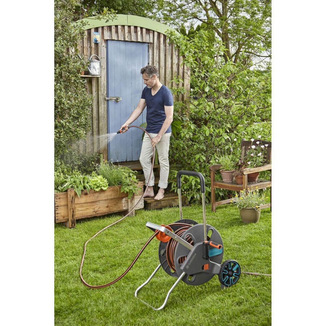 Person gießt mit Schlauchwagen CleverRoll L Easy Pflanzen im Garten.