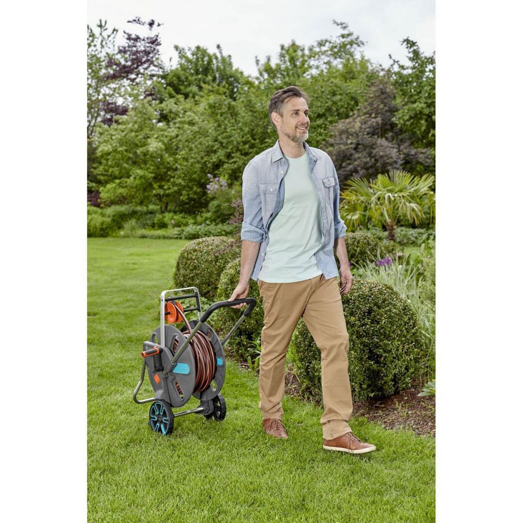 Person zieht einen Schlauchwagen durch den Garten.