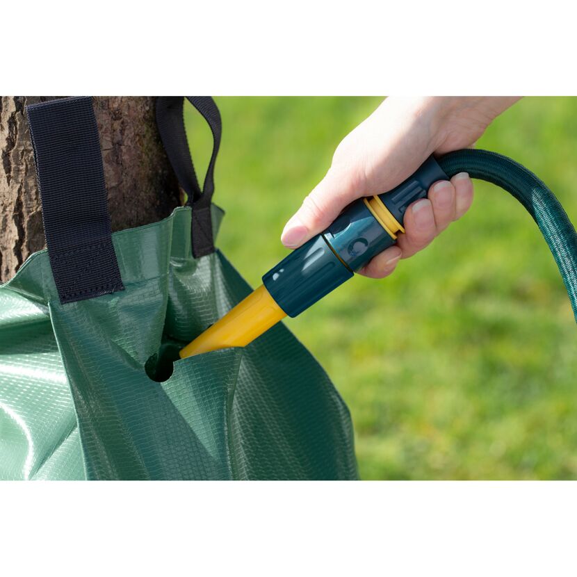 Eine Person befüllt einen Bewässerungssack mit einem Gartenschlauch.