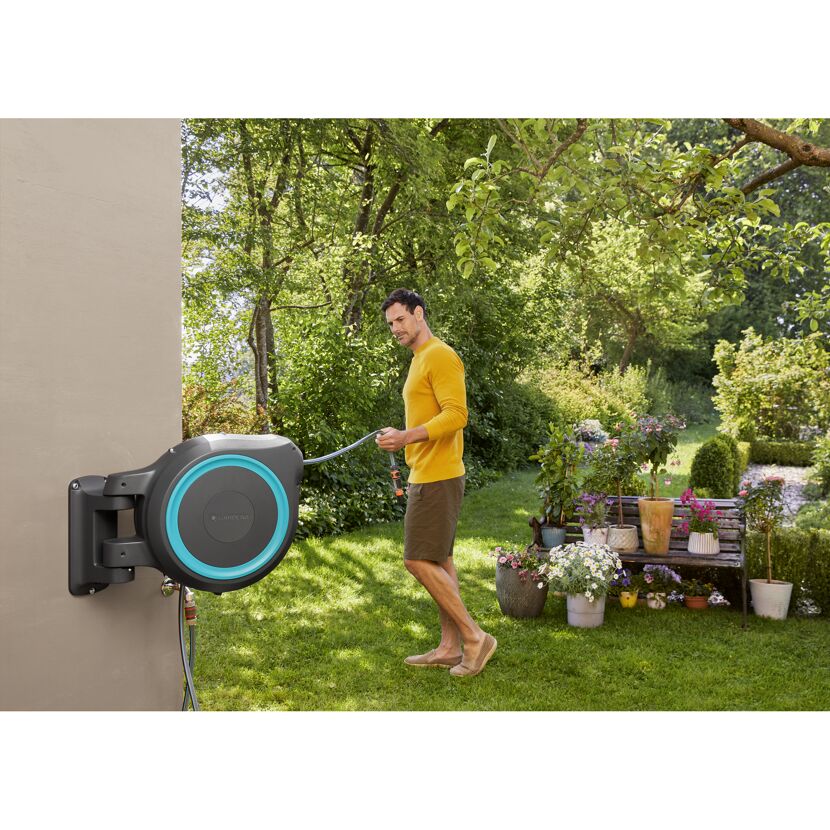 Person bewässert Garten mit Gardena Wand-Schlauchbox RollUp
