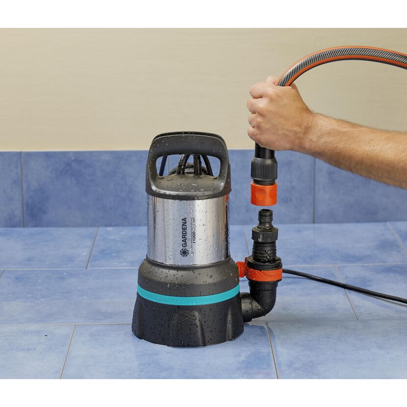 Person beim Anschließen eines Gartenschlauchs an eine Klarwasserpumpe