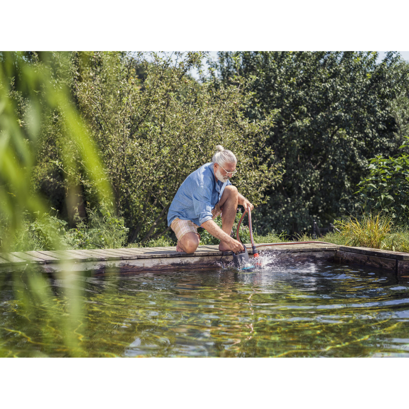 Person reinigt Pool mit Schmutzwasserpumpe