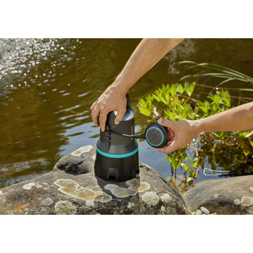 Person installiert Schmutzwasserpumpe am Teichrand.