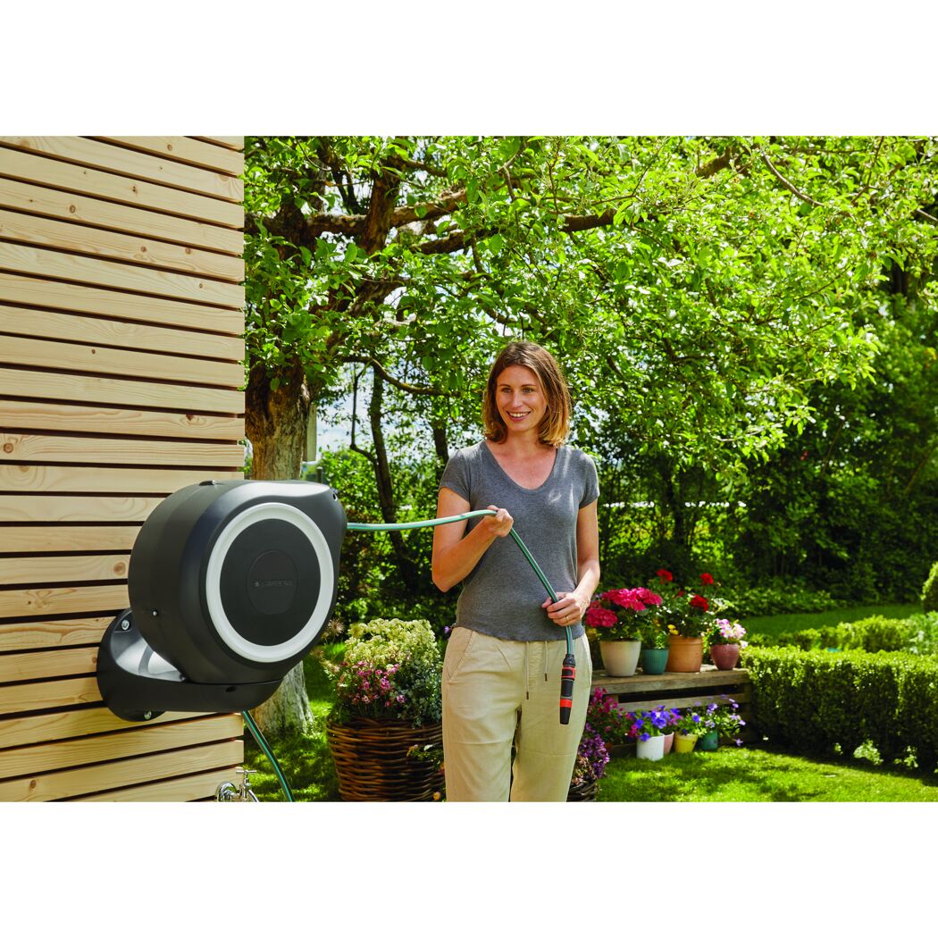 Person wickelt Gartenschlauch auf eine Gardena Wand-Schlauchbox RollUp S