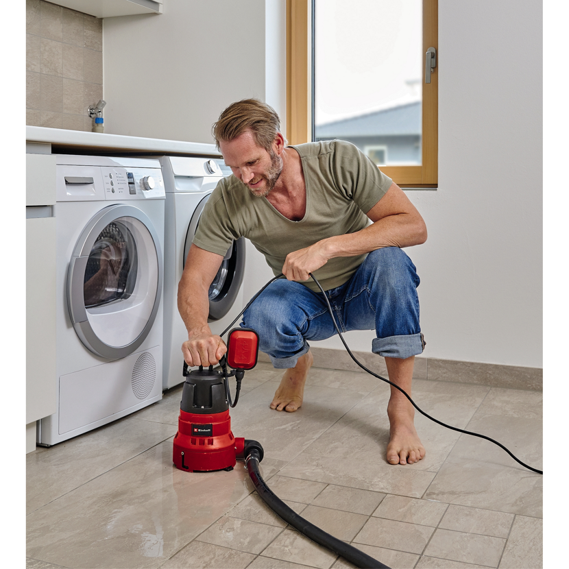 Person pumpt Wasser mit Tauchpumpe ab.