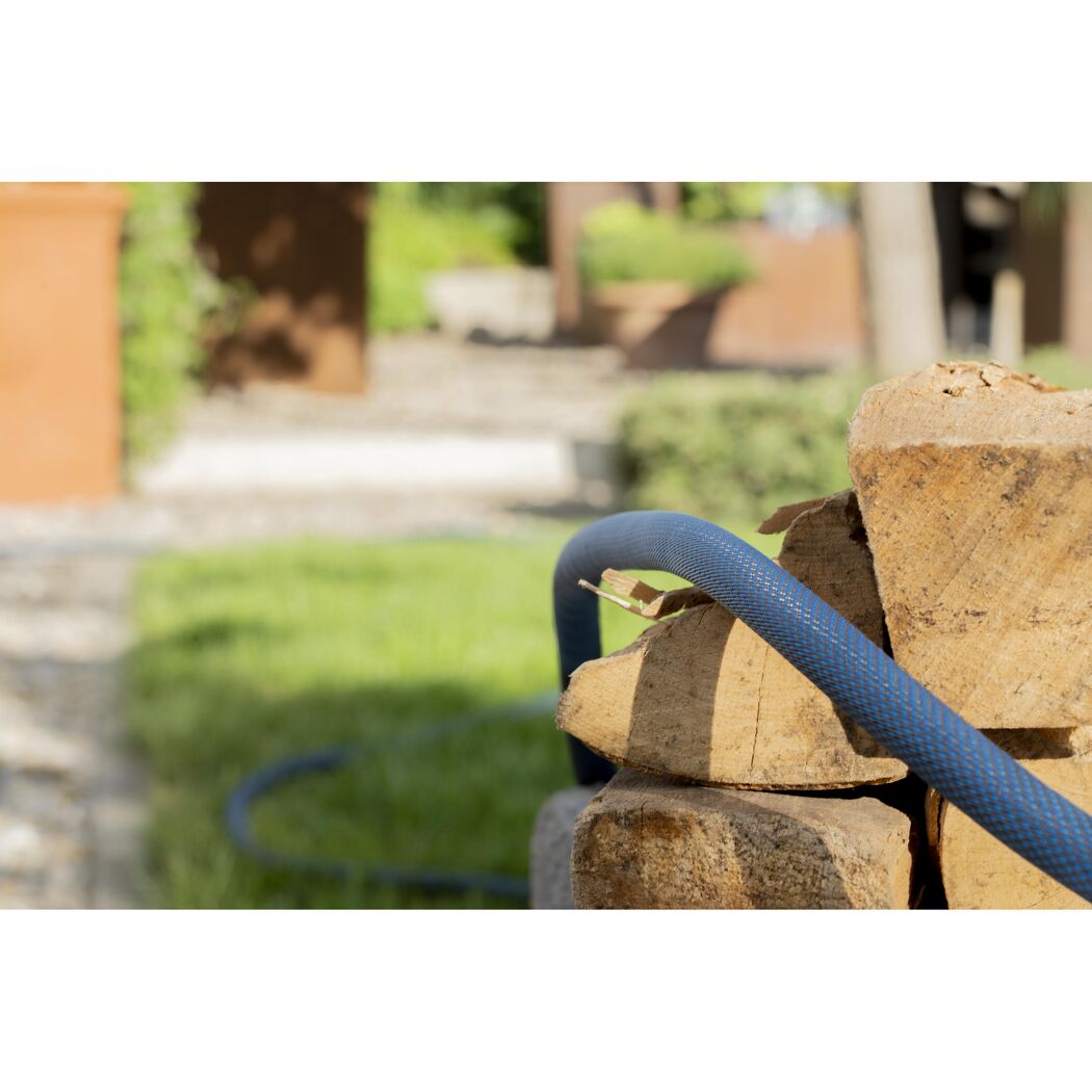 Blauer Gartenschlauch auf Holzstapel