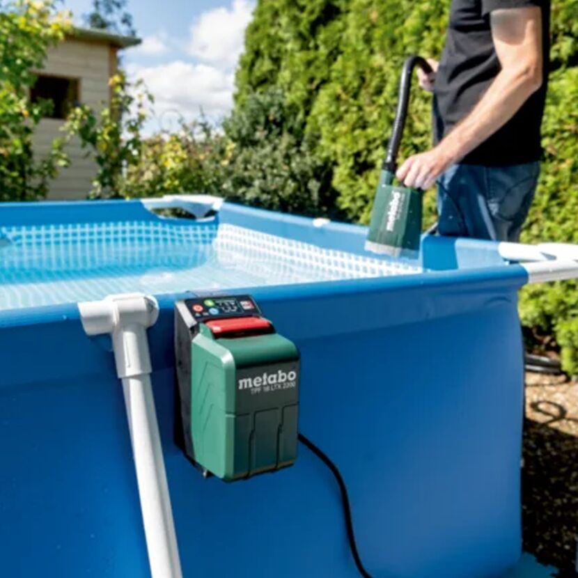 Person pumpt Wasser aus einem Pool mit einer Akku-Tauchpumpe