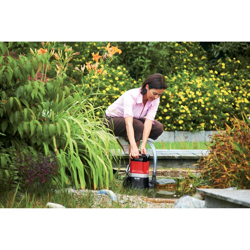 Person platziert Tauchpumpe am Teich