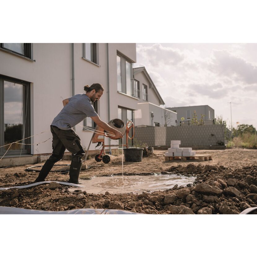 Person mit Schlauch und Betonmischer