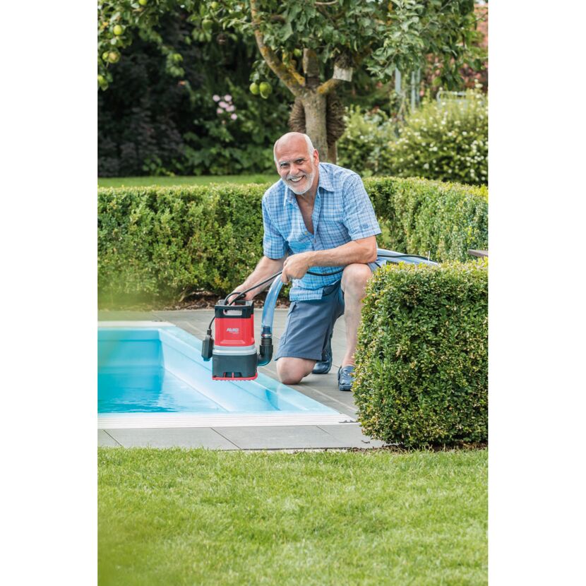 Person mit Tauchpumpe am Pool