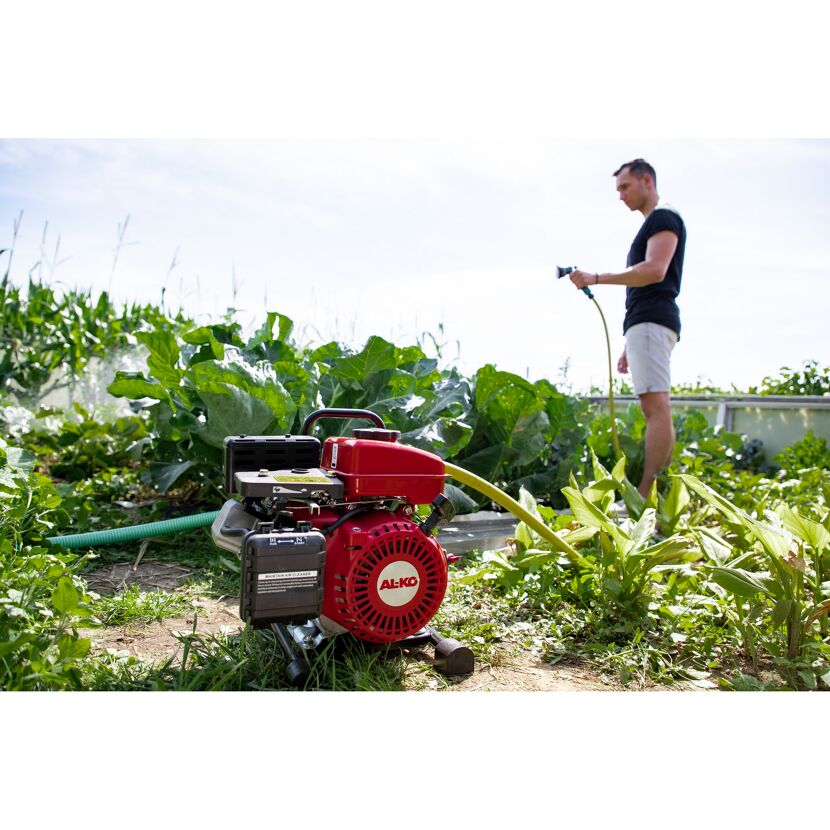 Person gießt Garten mit Benzinmotorpumpe