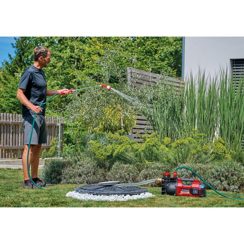 Person gießt mit Gartenpumpe