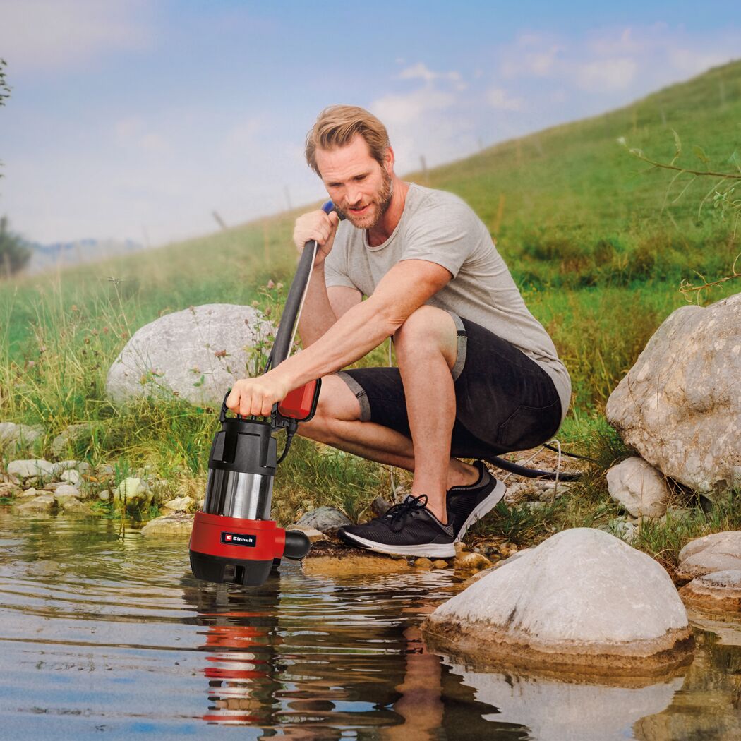 Person mit Schmutzwasserpumpe am Teich