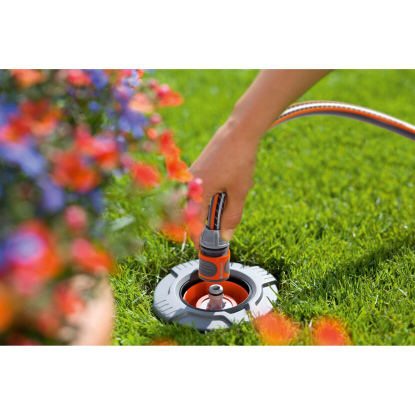 Person schließt Gartenschlauch an Wassersteckdose an.
