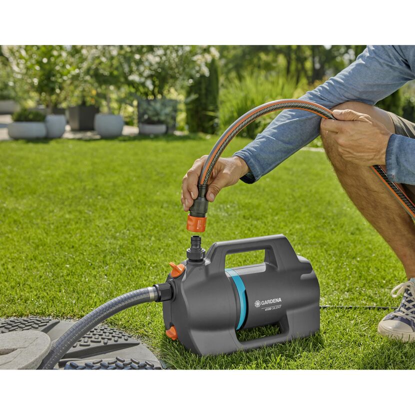 Person befestigt Schlauch an Gartenpumpe GARDENA 4100 Silent.
