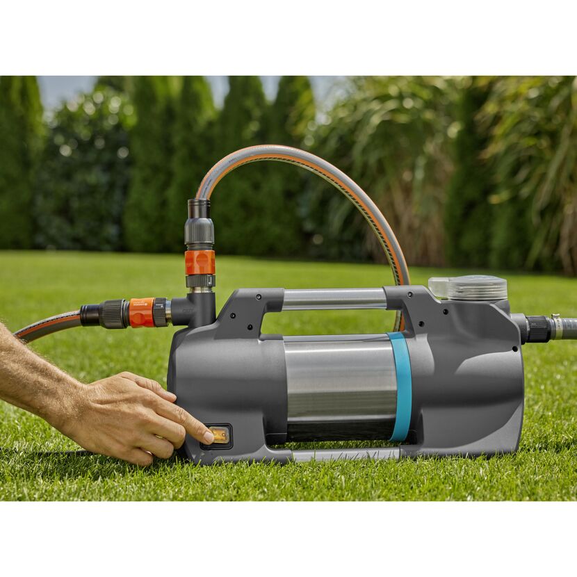 Person schaltet Gartenpumpe ein.