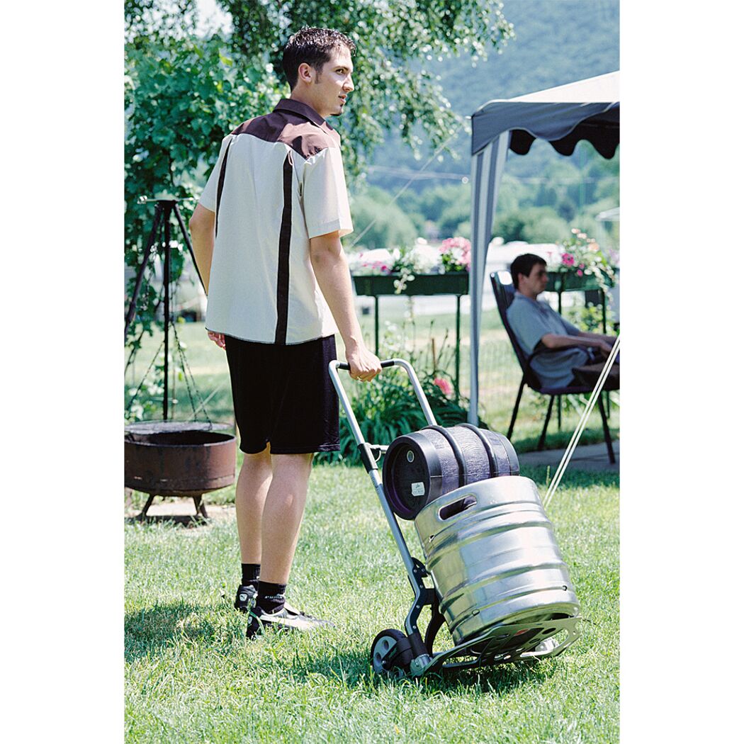 Person transportiert Fässer mit Transportkarre.