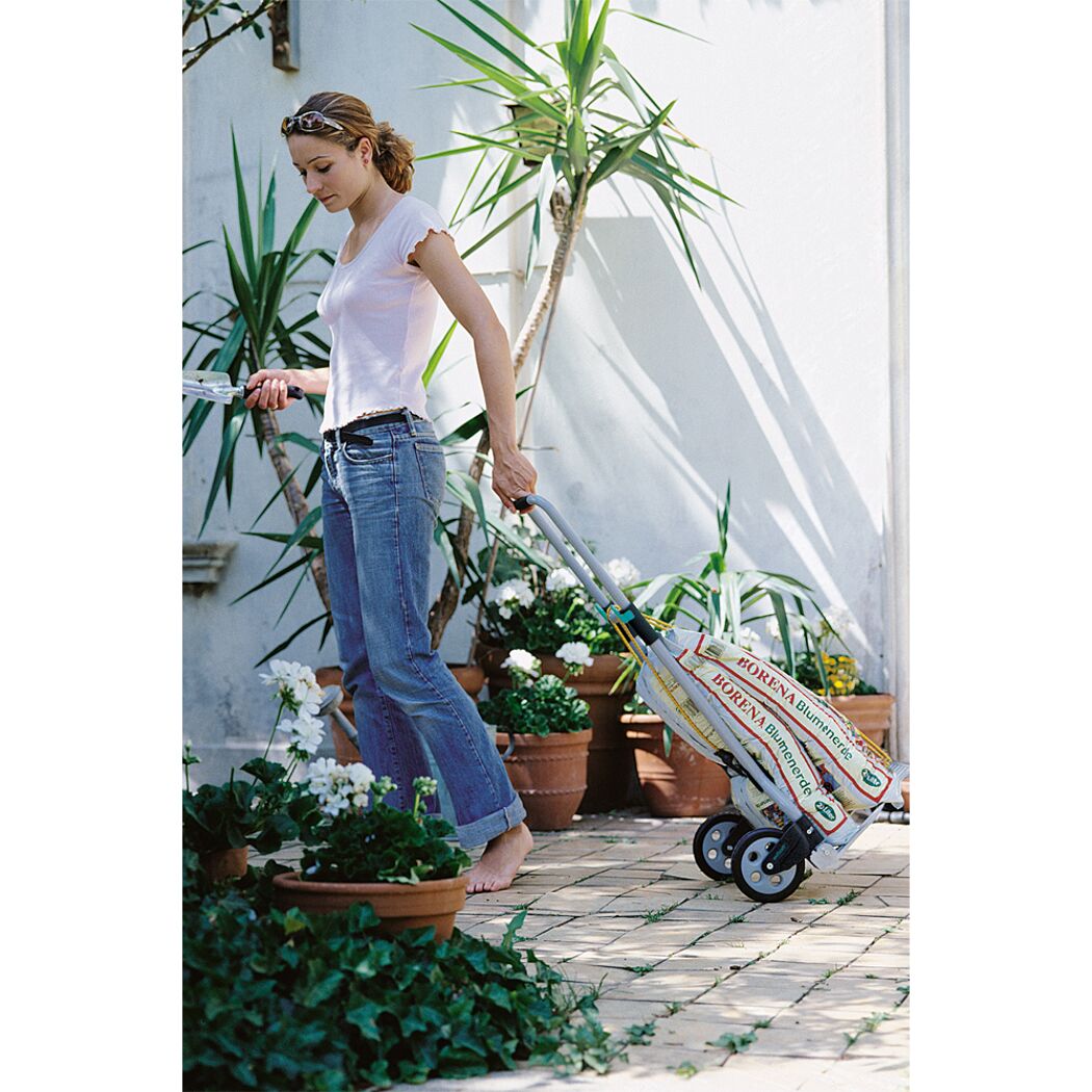 Person transportiert Blumenerde mit Transportkarre.