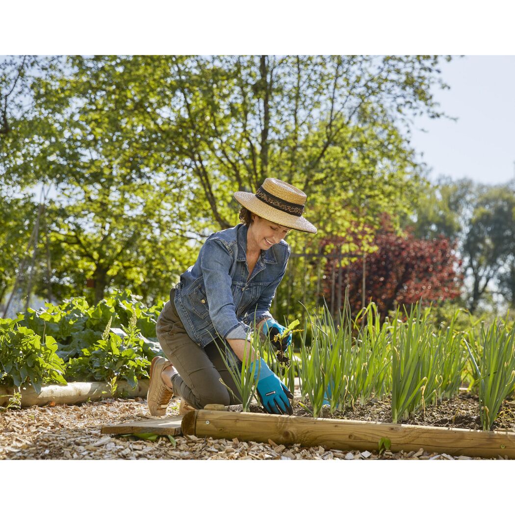 Person jätet mit Gartenhandschuhen Unkraut