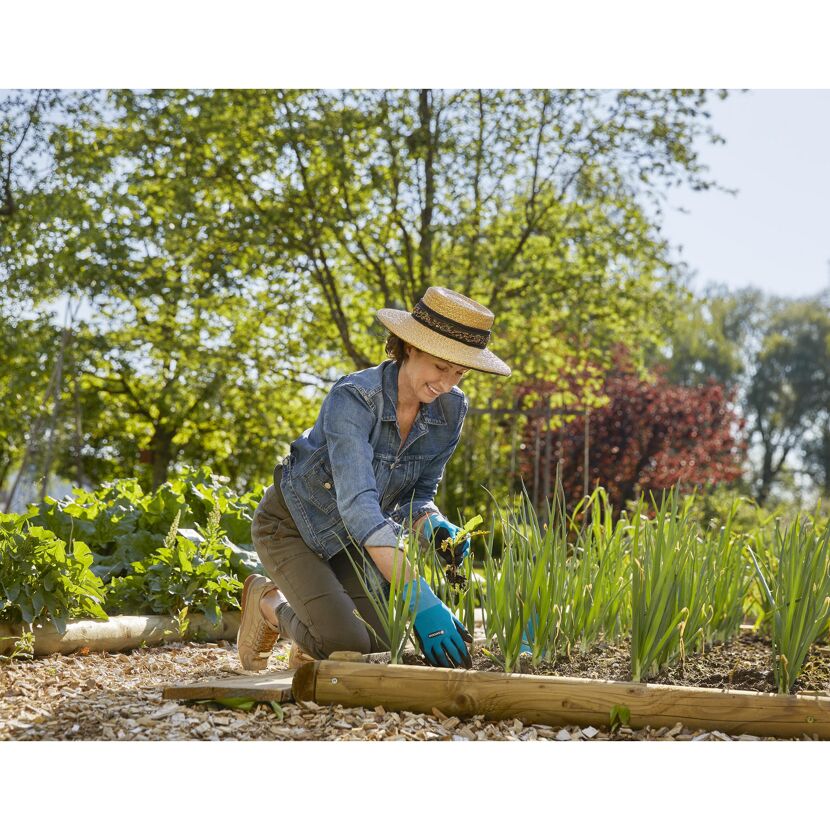 Person jätet mit Gartenhandschuhen Unkraut