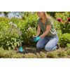 Person pflanzt Blumen mit Handschuhen und Kelle.